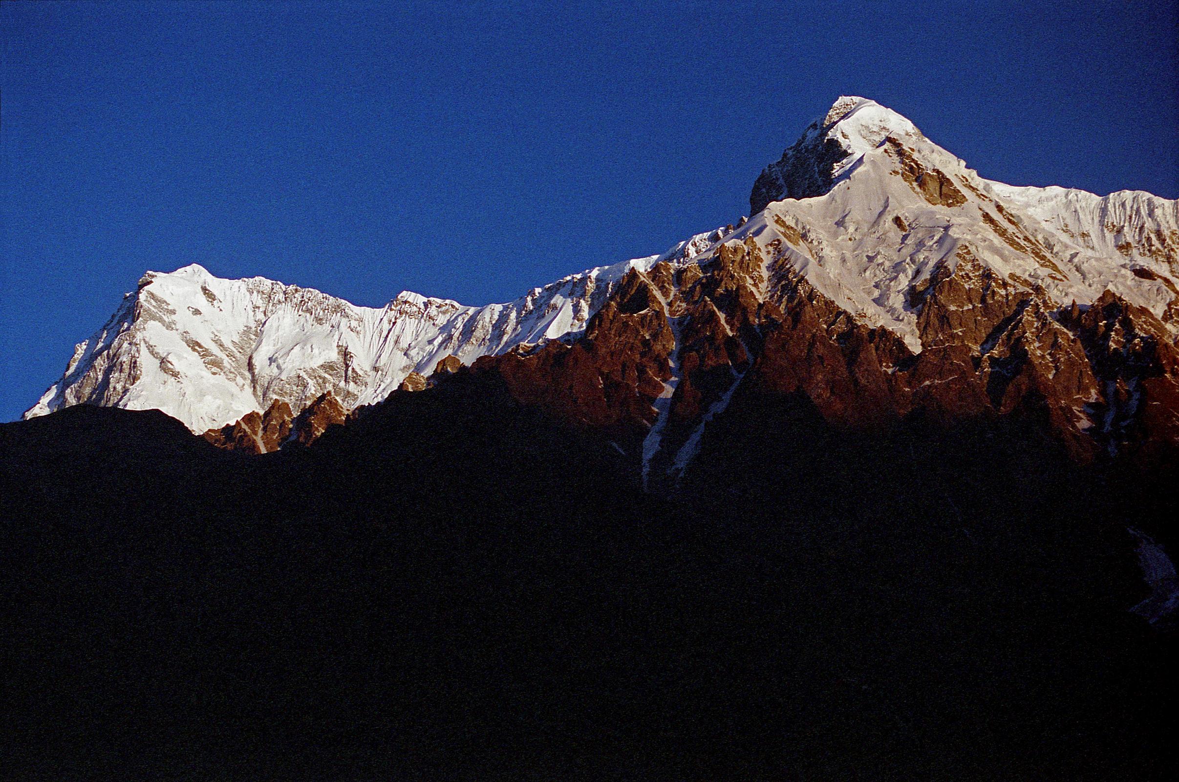 09 Nanga Parbat Rupal And East Faces, Rakhiot Peak From Tarashing At Sunrise The yellow light of sunrise quickly changes to white on the Nanga Parbat Rupal and East Faces from Tarashing. Rakhiot Peak is on the right. Gunther Messner�s diary May 15, 1970: The day dawns bright and cloudless. For the first time I see Nanga and Chongra Peak from the south: the impression is overwhelming. Huge hanging glaciers, terrifying precipices, furrowed by avalanches. Right over to the left is the summit of Nanga! (The Naked Mountain by Reinhold Messner)